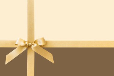 Bej ve kahverengi arka plan üzerinde bir hediye olarak bir yay ile Altın kurdele