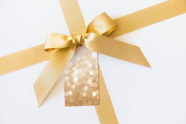 Beyaz bir arka plan üzerinde bir hediye olarak bir yay ile altın kurdele. Boş pa