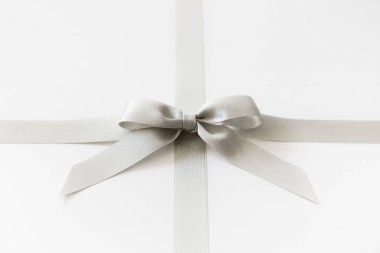 Beyaz arka plan üzerinde bir hediye olarak bir yay ile Gümüş kurdele