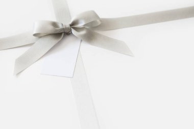 Beyaz arka plan üzerinde bir hediye olarak bir yay ile Gümüş kurdele