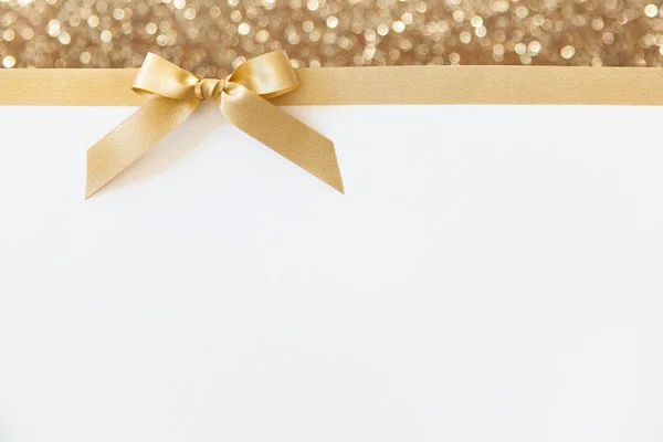 Cinta de oro con un lazo como regalo en una espalda brillante blanca y dorada — Foto de Stock