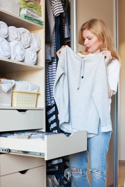 Het meisje overweegt een gestreepte jurk. Die hangt in de afdeling — Stockfoto