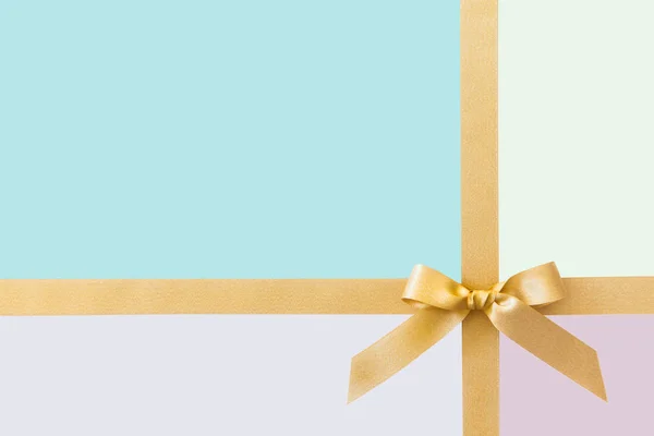 Guld band med en båge som en gåva på en pastellfärgad bakgrund — Stockfoto