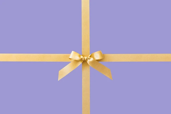 Zlatá stuha s lukem jako dar na fialovém pozadí — Stock fotografie