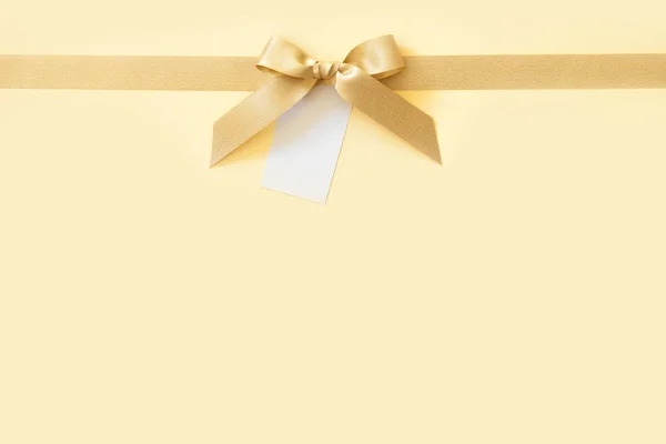 Ruban d'or avec un arc en cadeau sur fond beige — Photo