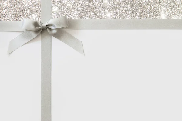 Zilveren lint met een strik als een geschenk op een witte en glanzende backgrou — Stockfoto