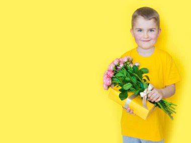 Sarı giyimli bir çocuk elinde büyük bir buket gül tutuyor ve. 