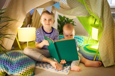 Çocuk çadırında kitap okuyan iki sevimli kardeş. 6 yıl ol