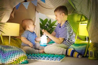 İki sevimli kardeş bir çocuk çadırında bir el feneri ile oynamak. 6