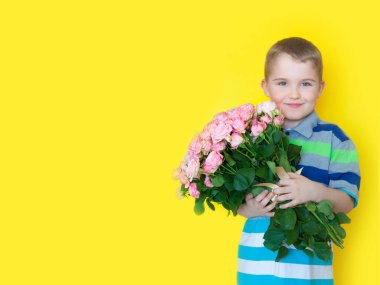 Çocuk elinde büyük bir buket gül ve bir hediye tutuyor. Sarı b