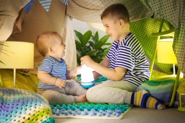 İki sevimli kardeş bir çocuk çadırında bir el feneri ile oynamak. 6