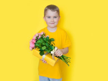 Sarı giyimli bir çocuk elinde büyük bir buket gül tutuyor ve. 