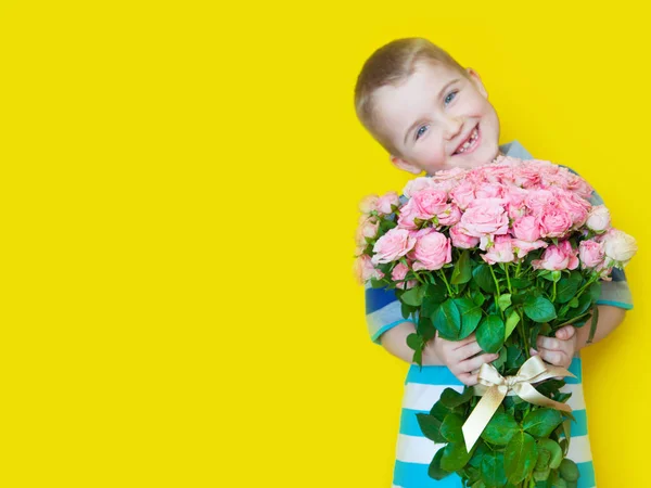 Pojken håller en stor bukett rosor och en gåva. Gul b — Stockfoto