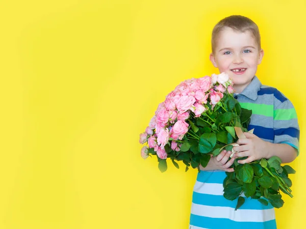 Pojken håller en stor bukett rosor och en gåva. Gul b — Stockfoto