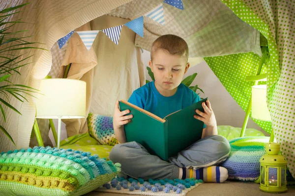 子供のテントで読書や家族のゲーム。本のbefを持つ少年 — ストック写真