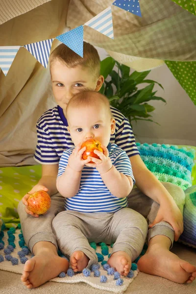 Två söta bröder äter äpplen i ett barn tält. 6 år gammal b — Stockfoto