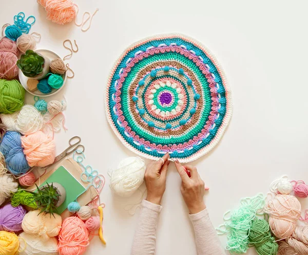 Mãos femininas que unem mandala redonda com lã a cores, em um branco — Fotografia de Stock