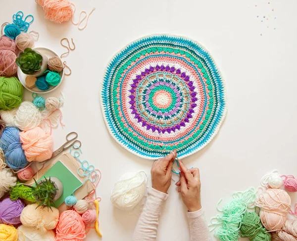 Mãos femininas que unem mandala redonda com lã a cores, em um branco — Fotografia de Stock