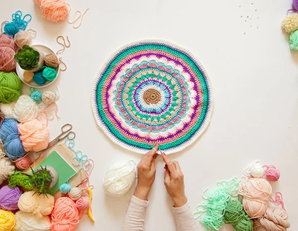 Weibliche Hände, die rundes Mandala mit Wolle stricken, auf einem weißen — Stockfoto