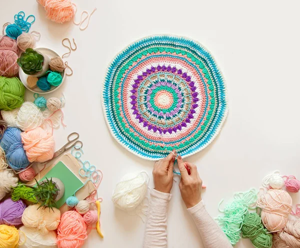 Mãos femininas que unem mandala redonda com lã a cores, em um branco — Fotografia de Stock