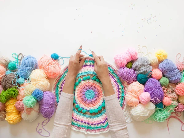Mãos femininas que unem mandala redonda com lã a cores, em um branco — Fotografia de Stock