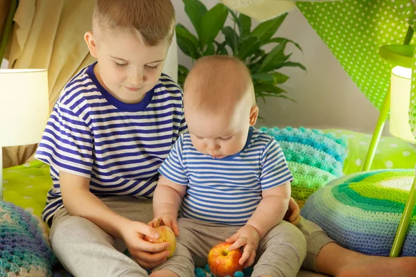 Two cute brothers eat apples in a children's tent. 6 years old b — Stock Photo, Image