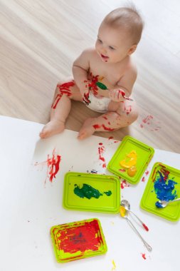 Bebek çocuk renkli boyalar elleri, kirli ayakları ile çizer. Beyaz li