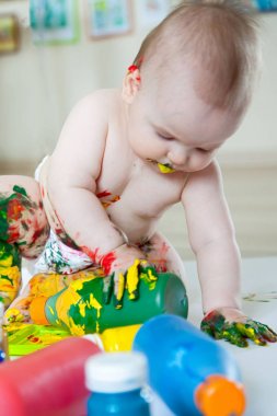 Bebek çocuk renkli boyalar elleri, kirli ayakları ile çizer. Beyaz li