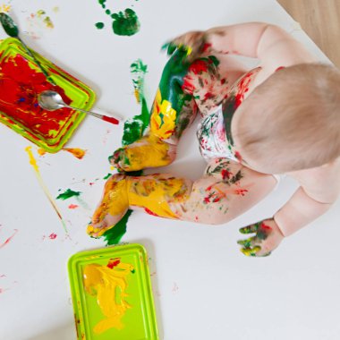 Bebek çocuk renkli boyalar elleri, kirli ayakları ile çizer. Beyaz li