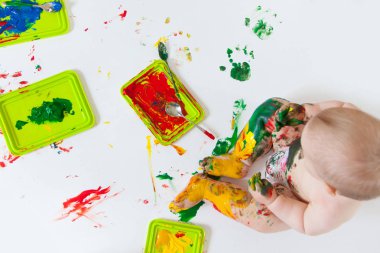 Bebek çocuk renkli boyalar elleri, kirli ayakları ile çizer. Beyaz li