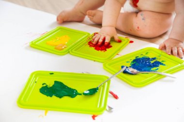 Bebek çocuk renkli boyalar elleri, kirli ayakları ile çizer. Beyaz li