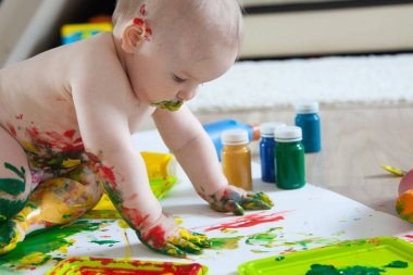 Bebek çocuk renkli boyalar elleri, kirli ayakları ile çizer. Beyaz li