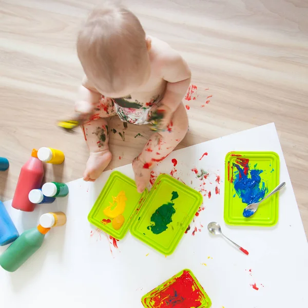 Bebé niño dibuja con pinturas de colores manos, pies sucios. Blanco li — Foto de Stock