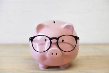 Ahşap arka planda gözlük ile domuzcuk Bankası