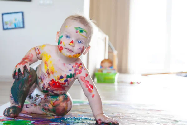 Bebé niño dibuja con pinturas de colores manos, pies sucios y dedos — Foto de Stock