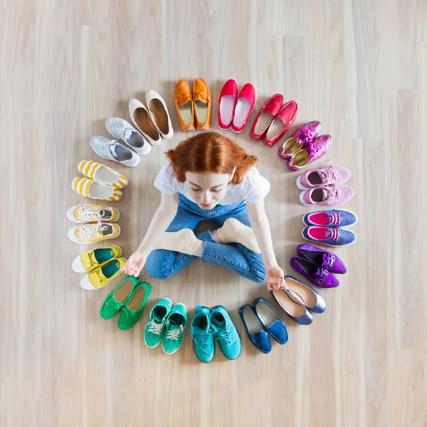 Menina escolhe sapatos no quarto no fundo de madeira — Fotografia de Stock