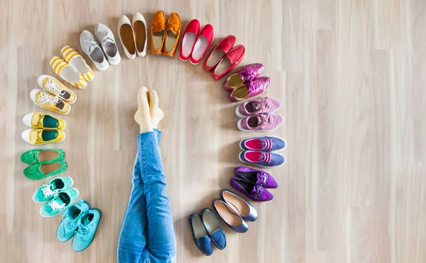 Menina escolhe sapatos no quarto no fundo de madeira — Fotografia de Stock