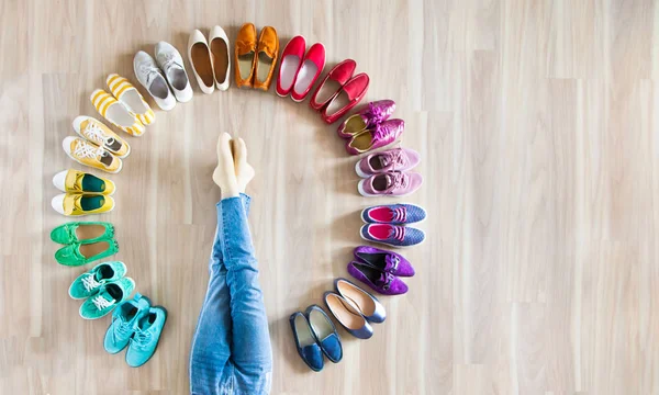 Dziewczyna wybiera buty w pokoju na drewnianym tle — Zdjęcie stockowe