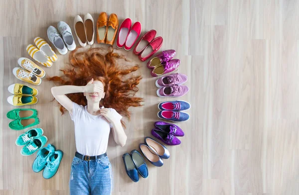 Menina escolhe sapatos no quarto no fundo de madeira — Fotografia de Stock