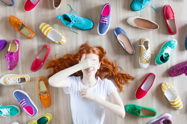 Muitos sapatos femininos coloridos no chão. Uma mulher escolhe-a — Fotografia de Stock