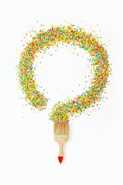 Un pincel de pintura pinta un círculo con confeti festivo de colores. ¿Qué? —  Fotos de Stock