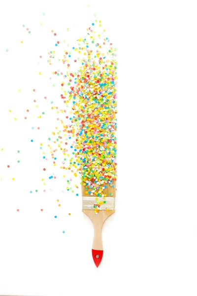 A paint brush draws a straight line with colored holiday confett — Stock Photo, Image
