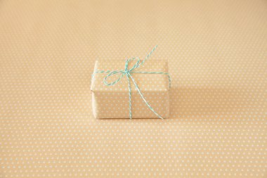 Açık mavi kurdeleli bej bir hediye. Köprü benekli sırt desenli.