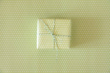 Benekli arka planda açık yeşil kurdeleli yeşil hediye.