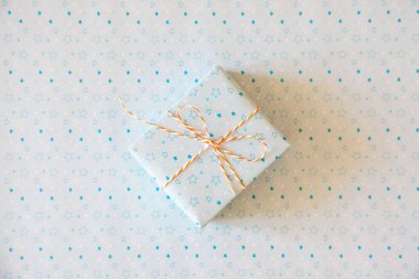 Beyaz arkaplanda yıldızlı kurdeleli açık mavi hediye.