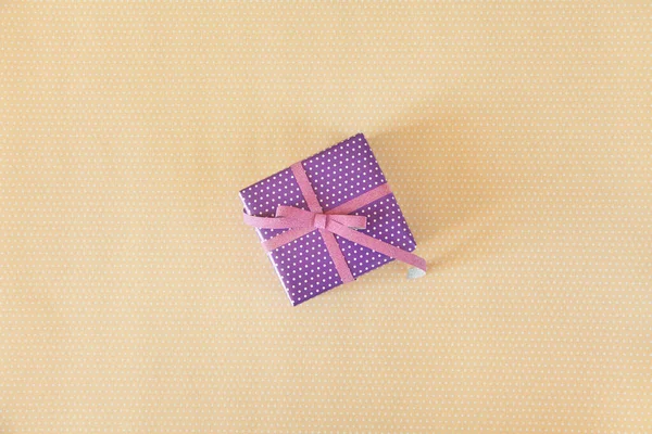 Regalo viola con nastro rosa sullo sfondo a pois brige — Foto Stock