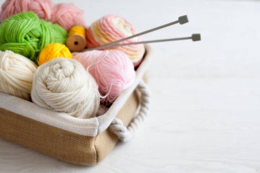 Sıcak, sade bir ortam. Kadın örgü hobisi. Sıcak renklerde iplik. Pembe, şeftali, bej, beyaz ve yeşil. Bir kadın süveteri örme sürecinin başlangıcı.