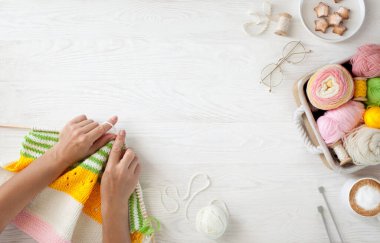 Sıcak, sade bir ortam. Kadın örgü hobisi. Sıcak renklerde iplik. Pembe, şeftali, bej, beyaz ve yeşil. Bir kadın süveteri örme sürecinin başlangıcı.