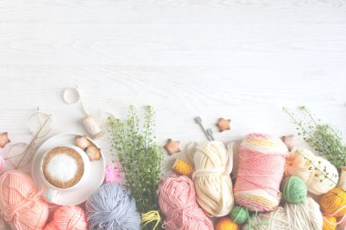 Sıcak, sade bir ortam. Kadın örgü hobisi. Sıcak renklerde iplik. Pembe, şeftali, bej, beyaz ve yeşil. Bir kadın süveteri örme sürecinin başlangıcı. İplik çerçevesi.