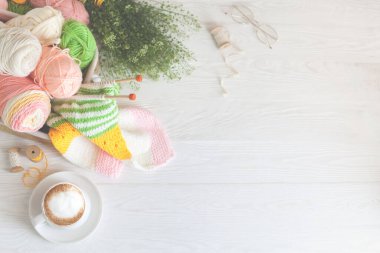 Sıcak, sade bir ortam. Kadın örgü hobisi. Sıcak renklerde iplik. Pembe, şeftali, bej, beyaz ve yeşil. Bir kadın süveteri örme sürecinin başlangıcı.